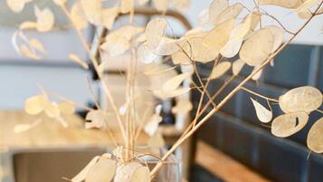 A clear glass vase with dried leaves on a wooden table.