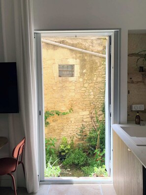 Ein Zimmer mit einer Steinsäule, einem kleinen Fenster und Blick auf einen Garten.