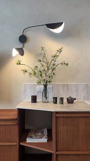 A kitchen counter with a vase of flowers, a teapot, and a magazine.