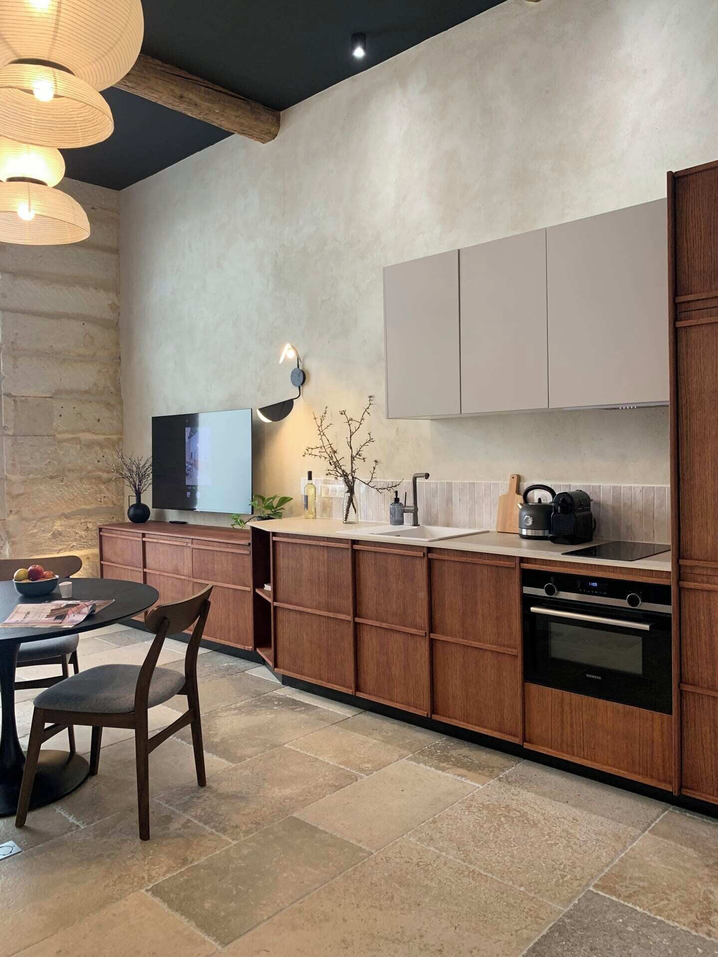 Una cucina moderna con mobili in legno, forno integrato e zona pranzo con tavolo e sedie.