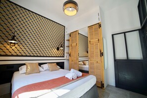 Ein Hotelzimmer mit einem großen Bett, einer Wand mit Muster, einem Kleiderschrank und einem Spiegel.