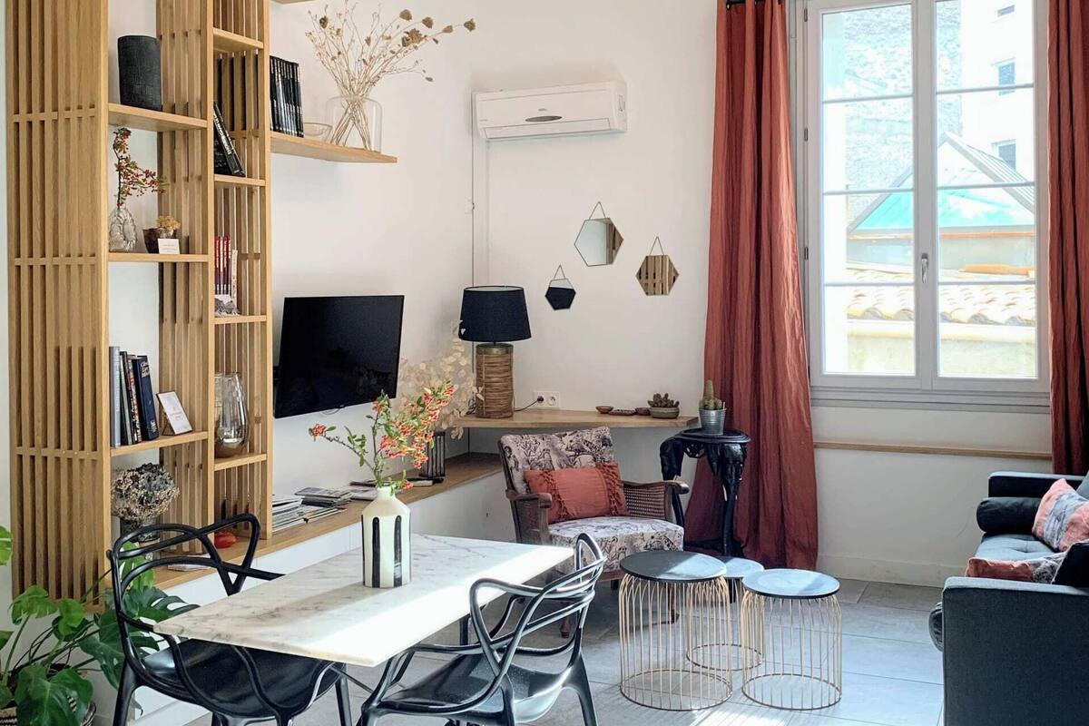 Ein modernes Wohnzimmer mit Essbereich, ausgestattet mit Fernseher, Bücherregalen, einem Couchtisch und einer Couch.