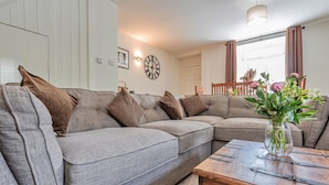 A modern living room with a grey sectional sofa, a wooden coffee table, and a vase with flowers. - Blaen Ddol (Betws-Y-Coed)