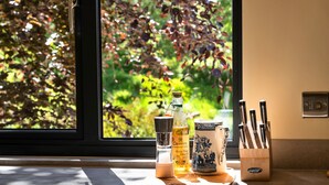 Un piano di lavoro in cucina con un condimento per sale e pepe, una bottiglia d'olio d'oliva e una tazza di ceramica con un portacoltelli.