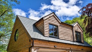 Una baita di legno con tetto a capanna, un portico coperto e un'ampia finestra circolare.
