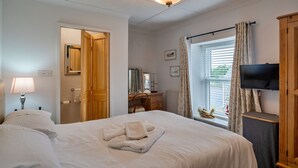 Une chambre d’hôtel avec un lit, un bureau, une télévision et une fenêtre avec des rideaux.