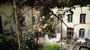 A courtyard with a tree, a white fence, and a building with windows and shutters. - Bel Appartement de 110m2 Dans un Hôtel Particulier du Xviiie Siècle (Salins-les-Bains)