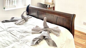 Een slaapkamer met een bed, een raam met zonwering, een nachtkastje, een stoel en een schilderij aan de muur.