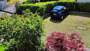 A residential area with a paved driveway, a parked car, and well-maintained hedges. - Your nest in Manerba (manerba del garda)