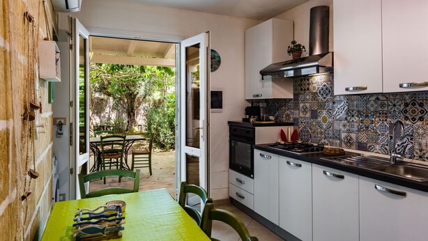 Una cocina compacta con armarios blancos, una estufa negra y un salpicadero de azulejos.