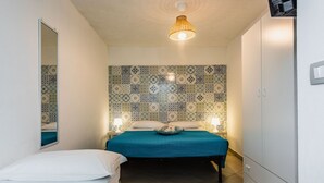 Un dormitorio con cama, mesitas de noche, un armario y un papel tapiz estampado.