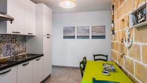 Una cocina con armarios blancos, un salpicadero de azulejos y una mesa amarilla con sillas.