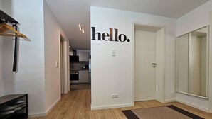 Ein Flur mit Holzboden, einem Kleiderständer und einer Tür mit einem 'hello' Schild.