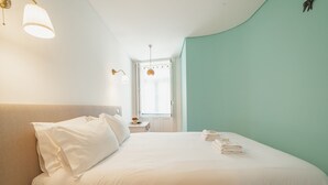 A hotel room with a bed, a nightstand, a lamp, and a window. - Downtown Charming by Vacationy (Porto)