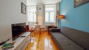 A living room with a TV, sofa, chairs, and a table with a lamp. - Downtown Charming by Vacationy (Porto)