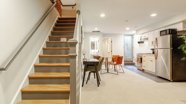 A modern kitchen with a built-in microwave and refrigerator, a dining area with a table and chairs, and a staircase with wooden steps and a metal railing. - Garage, King Bed, and Queen Pullout in Cap Hill. Two Blocks to Metro/Restaurants (Washington)