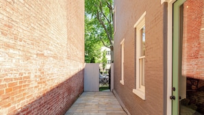 A narrow brick alleyway with a tiled walkway, a green door, and a window on the right. - Garage, King Bed, and Queen Pullout in Cap Hill. Two Blocks to Metro/Restaurants (Washington)