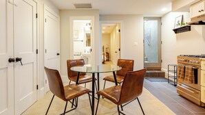 A dining area with a glass table and four leather chairs, a kitchen with a stove and oven, and white doors. - Garage, King Bed, and Queen Pullout in Cap Hill. Two Blocks to Metro/Restaurants (Washington)