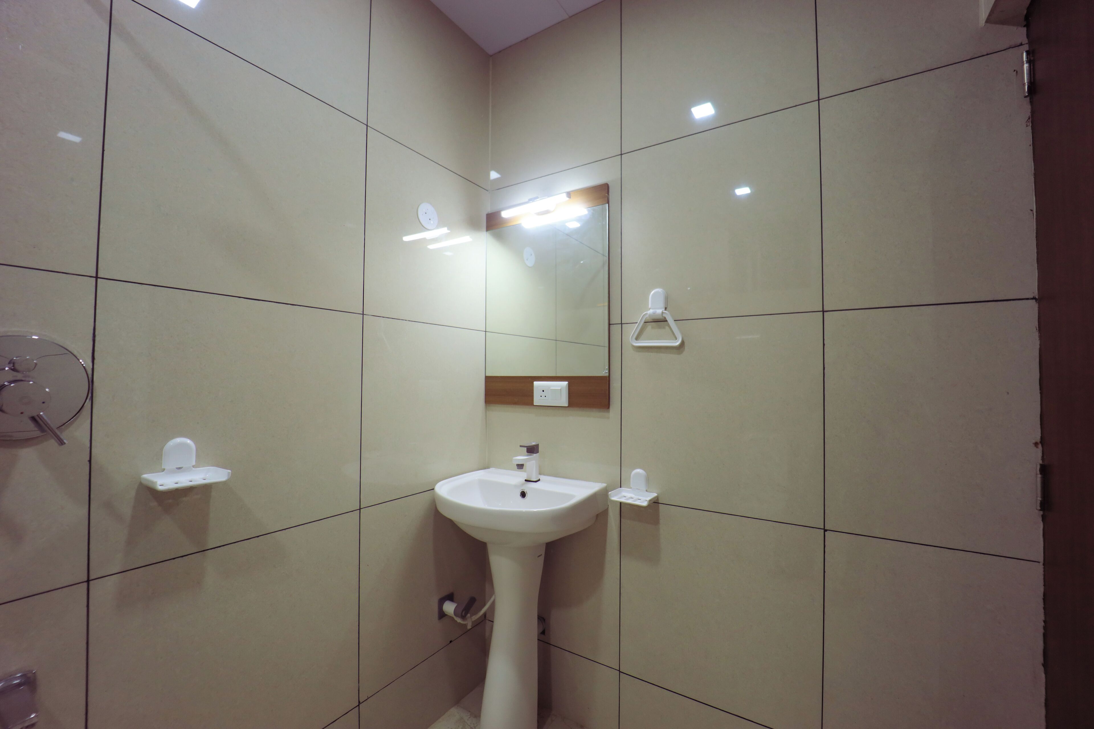 Un baño con lavamanos pedestal, un espejo y un perchero para toallas.