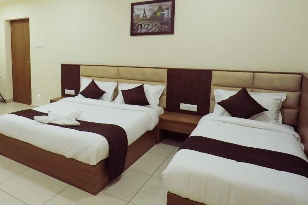 Une chambre d’hôtel avec deux lits, chacun doté d’une tête de lit marron et de draps blancs.