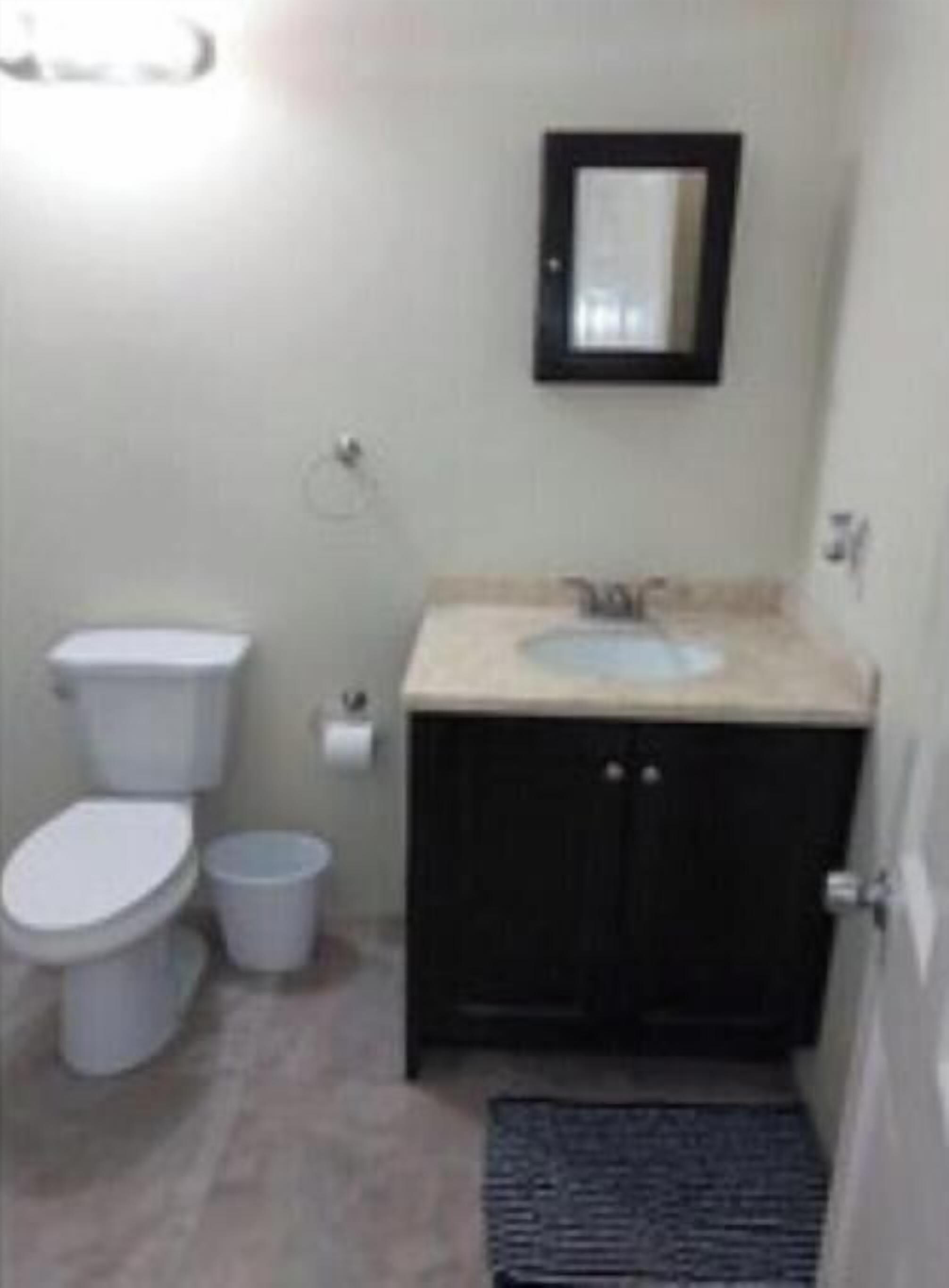A small bathroom with a toilet, sink, and mirror.
