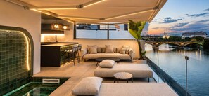 A modern balcony with a pool, seating area, and a view of a bridge and cityscape. - Casakary Sevilla (Seville)