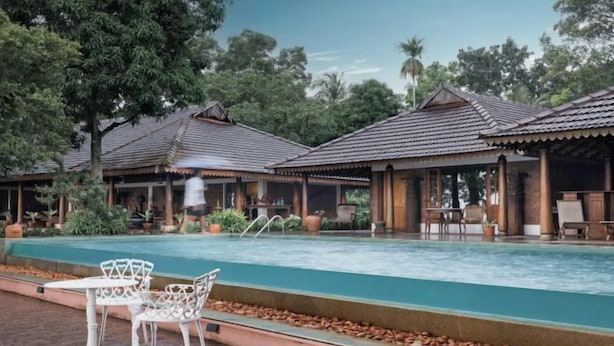 Un espace piscine avec des chaises blanches et un coin salon abrité.
