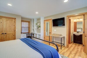 A bedroom with a bed, a television, a desk, and a wardrobe.