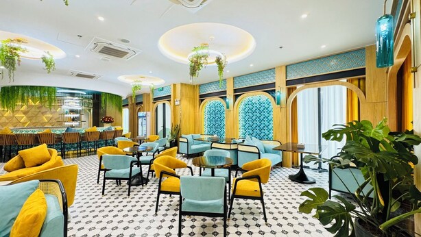 A modern interior with a bar area, seating with yellow and blue chairs, and decorative plants. - SIREN HOTEL HAI TIEN (Hoang Tien)