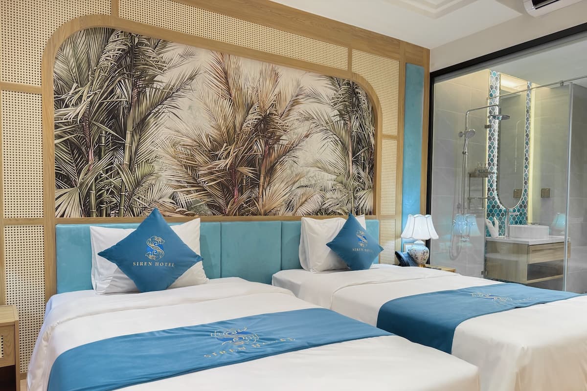 Hotelkamer met twee bedden, een groot wanddecor en een douchegedeelte, plus een nachtkastje.