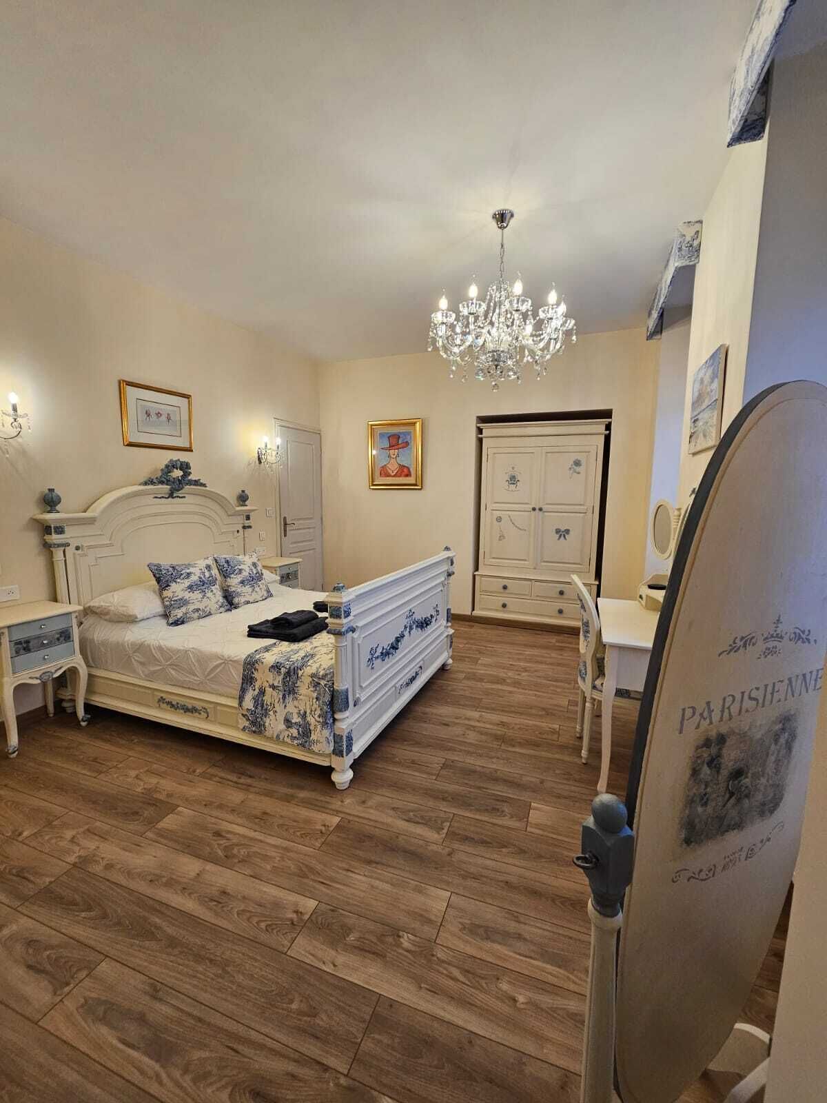 A bedroom with a large bed, a dresser, a chair, and a desk.