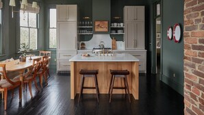 Uma cozinha com uma ilha central, cadeiras de madeira e uma mesa de jantar.