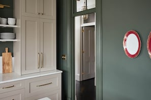 A kitchen with white cabinets, a wooden cutting board, and a white countertop.