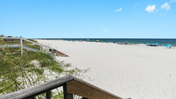 A beach with a wooden walkway leading to a sandy area. - Waterfront Gulf Shores Condo w/ Beach Access (Gulf Shores)