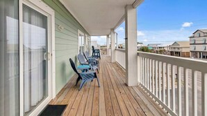 A covered porch with wooden flooring and white railings, featuring several chairs and a table. - Waterfront Gulf Shores Condo w/ Beach Access (Gulf Shores)