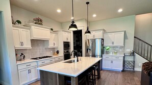 A spacious kitchen with white cabinets, a large island, and a wooden floor.