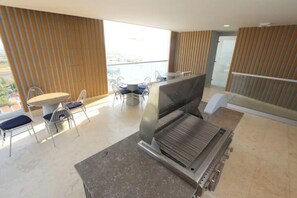 Ein modernes Zimmer mit großem Fenster, einem Essbereich mit Stühlen und Tisch sowie einem integrierten Grill.