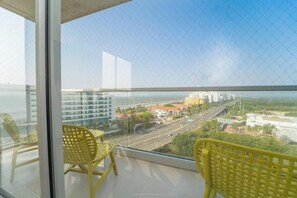 Relax and dine with a view of the city from this balcony, featuring two chairs and a table.