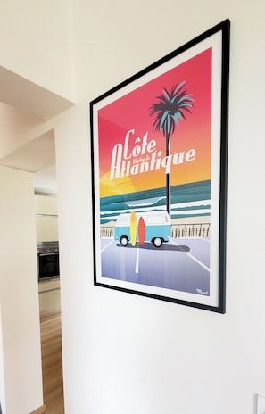Artwork 'Côte d'Azur - The Antique' adorns the wall, featuring a vintage van with a surfboard against a serene ocean backdrop.