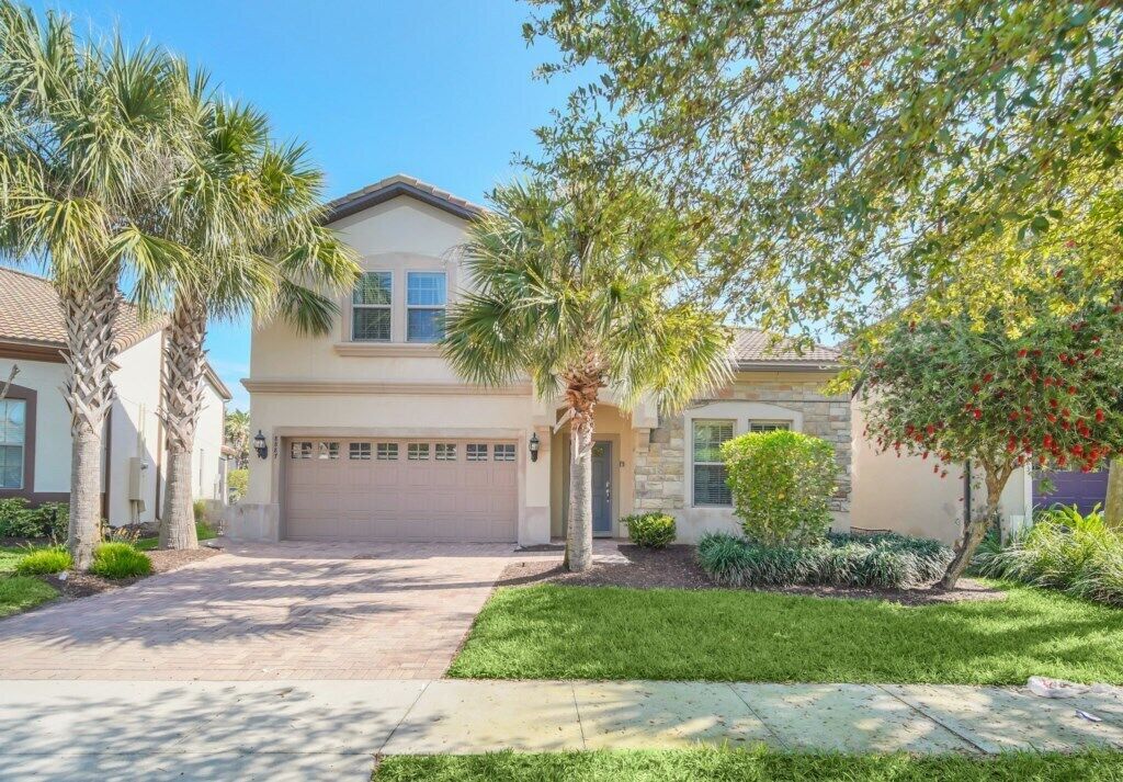 A residential house with a garage, palm trees, and a well-maintained lawn.