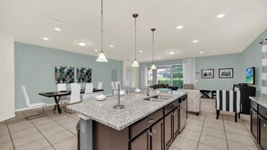 Una cocina moderna con encimeras de granito, una isla central e iluminación colgante.
