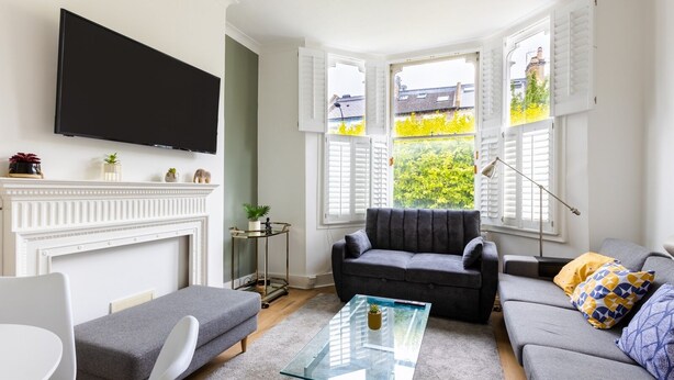 Ett modernt vardagsrum med en öppen spis, en soffa, ett soffbord och en tv som är monterad på väggen.