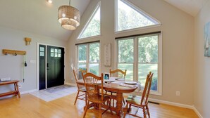 A dining area with a wooden table and chairs, large windows, and a hanging light fixture. - Smith Mountain Lake Home w/ Private Hot Tub & Dock (Moneta)