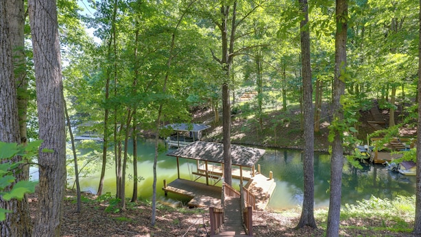 A wooden deck leading to a covered area with a view of a lake and dock. - Smith Mountain Lake Home w/ Private Hot Tub & Dock (Moneta)