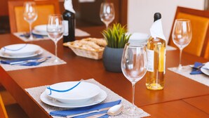A dining table set with plates, cutlery, and wine glasses, with a bottle of wine and a small plant on the table. - Villa with heatable saltwater pool in Galé (Albufeira)