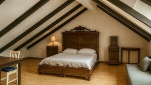 A bedroom with a wooden bed, a nightstand, a chair, a sofa, and a tall wooden cabinet. - Casa Milano - S. Alessandro 3 - Check-in in via Lupetta 5 (Milan)