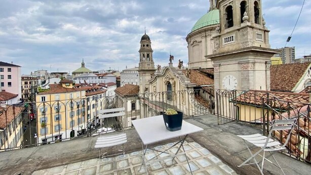 A rooftop terrace with a potted plant, a white table, and metal chairs. - Casa Milano - S. Alessandro 3 - Check-in in via Lupetta 5 (Milan)