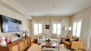 A living room with a sofa, armchairs, a coffee table, and a TV. - Modern beachfront condo with private deck, harbor views, and parking! (Provincetown)