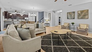 A spacious living area with a sofa, armchairs, a coffee table, and a ceiling fan.