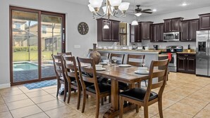 A modern kitchen with dark cabinets, stainless steel appliances, and a dining area with a table and chairs.